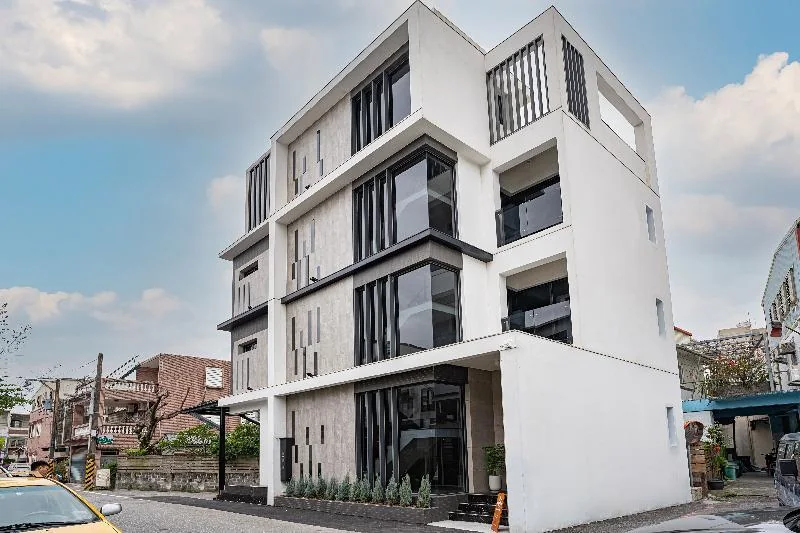 光粼Blinghouse白色外牆、深色窗框與欄杆的街角建築