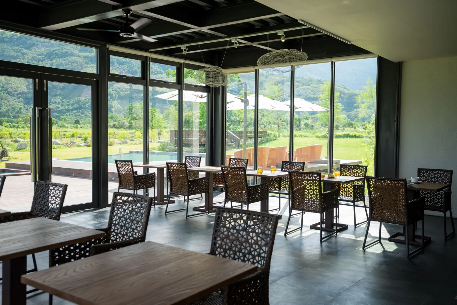 松邑莊園餐廳的編織椅面座椅與玻璃窗，窗外是木棧平台和草地