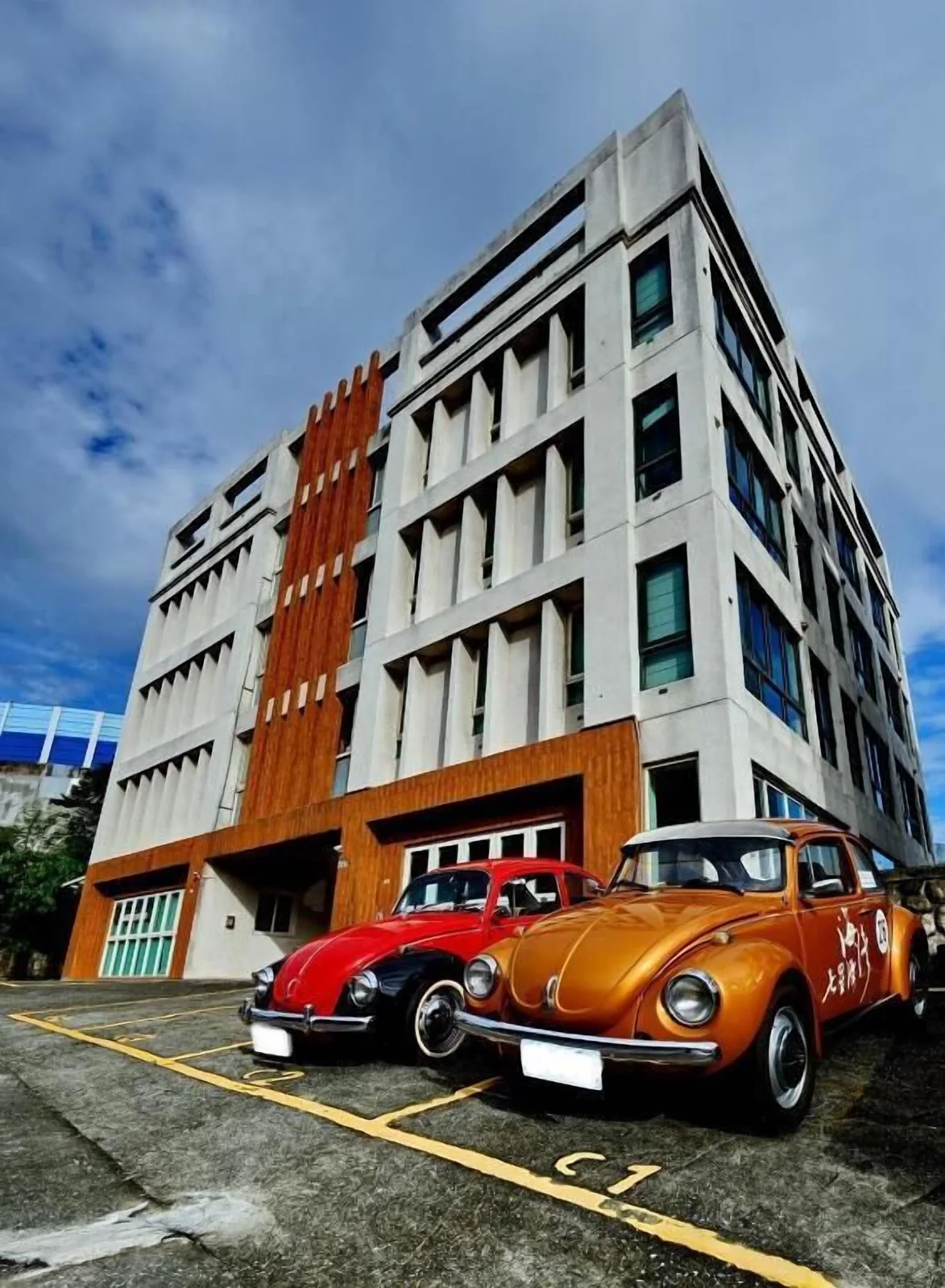 白灰橘立面建築前的兩輛彩色復古車