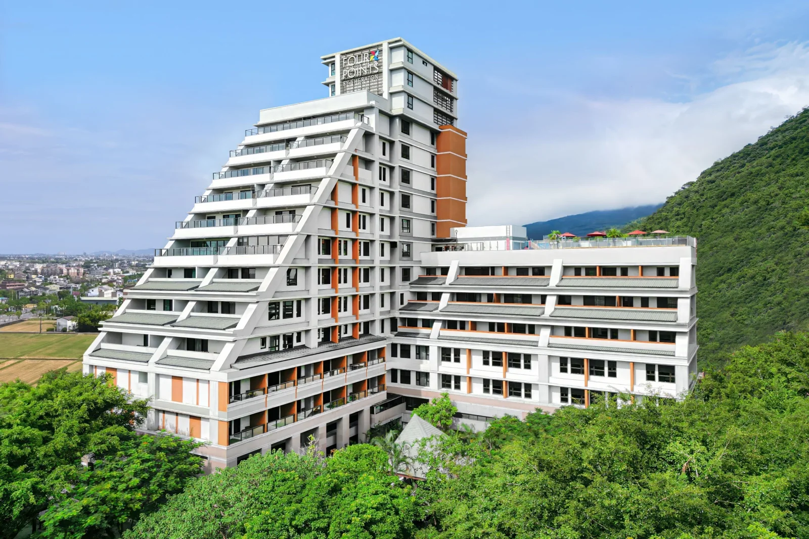 福朋喜來登白灰階梯形建築、橘色立面與山坡綠意