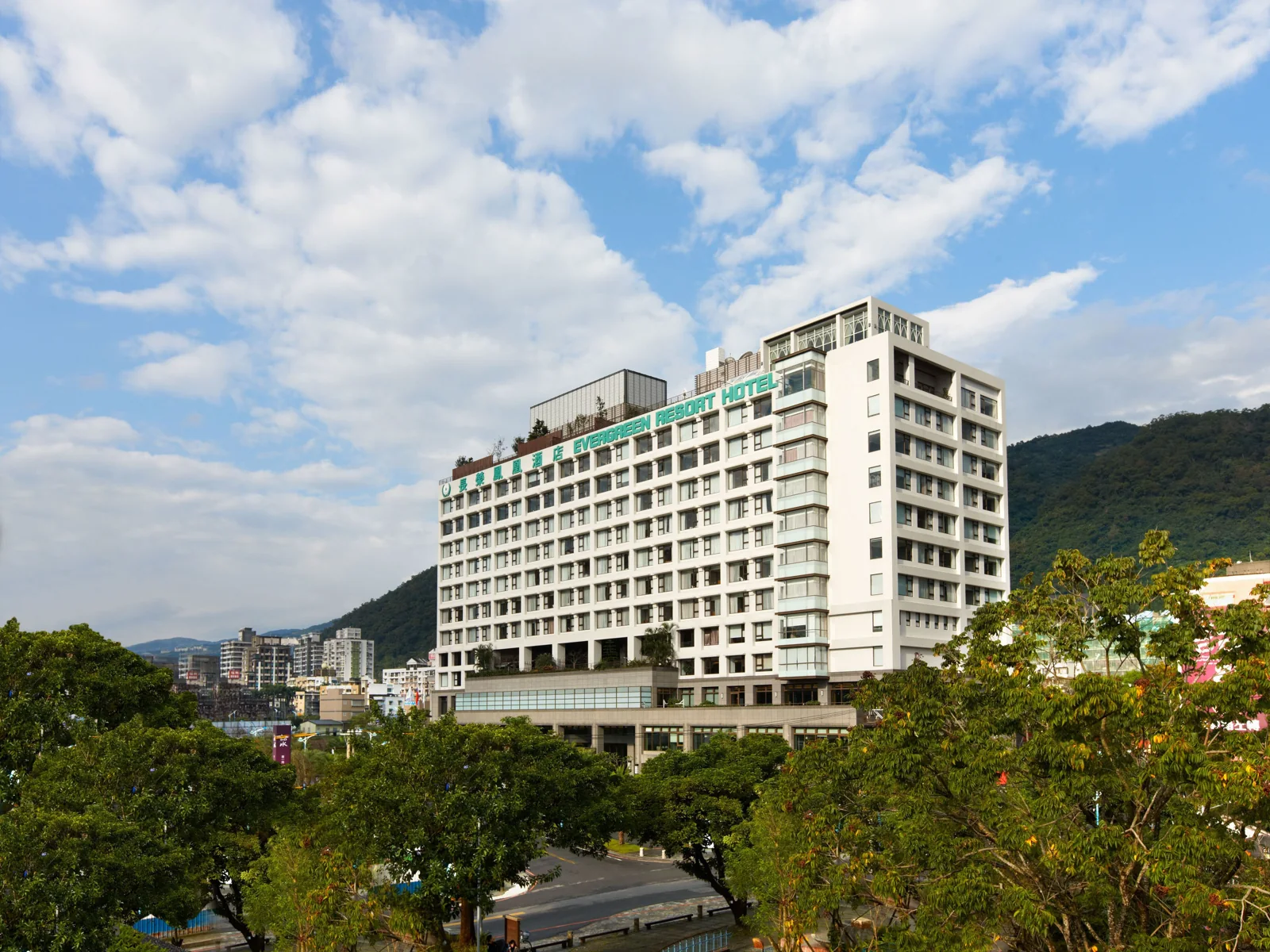 長榮鳳凰礁溪白色高樓、綠色招牌與山景樹木